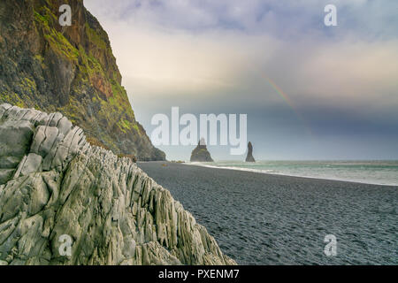Reynisfjara schwarzer Sandstrand mit erstaunlichen Basaltsäulen Formationen, eine gewölbte Covern und Meer Felsen sichtbar vom Strand in Island Stockfoto