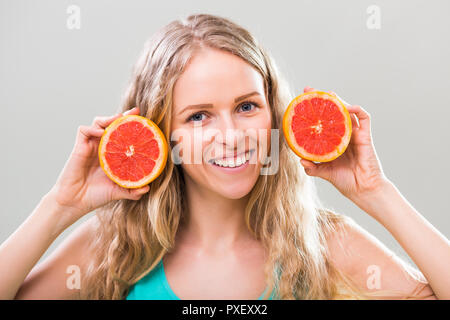 Schöne junge Frau mit Schichten von Grapefruit auf grauem Hintergrund. Stockfoto
