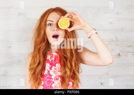 Junge Frau mit, die Augen mit zwei Scheiben Zitronen aufgeregt Stockfoto