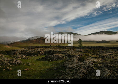 Landschaft an einem bewölkten Sommermorgen. wandern über die Lavafelder mit tief liegenden Wolken im Fuss. Proletariats, Arkhangai, Mongolei Stockfoto