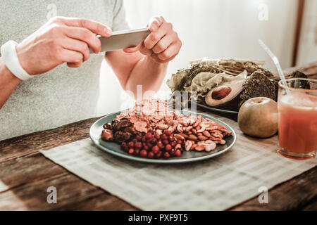 Schönen angenehmen jungen Mann sein Smartphone Holding Stockfoto