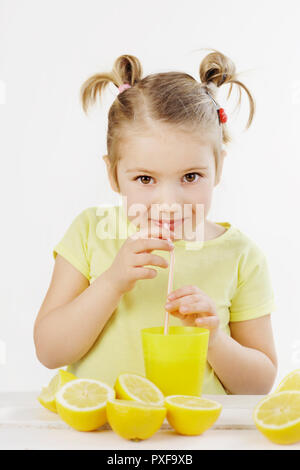 Süße kleine Mädchen trinken eine Limonade mit einem bemühten sich in ihren Augen auf dem weißen Hintergrund suchen Stockfoto