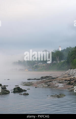 Northern Quebec nebligen Abend mit Leuchtturm und Dorf Vertikale Stockfoto
