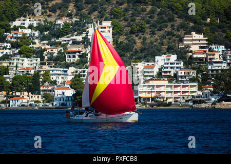 Segelyacht unter Red gennaker geht entlang der griechischen Küste der Ägäis. Stockfoto