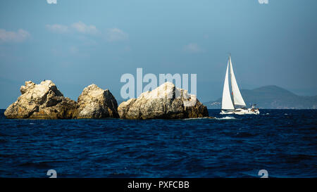 Yacht Boot mit weissen Segeln in der Nähe der Felsen in der Ägäis. Stockfoto