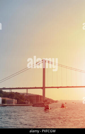 Blick auf Fähren und Ausflugsschiffe am Bosporus in Istanbul. Die Brücke ist auch in der Ansicht. Sonnenuntergang licht Effekt wird angewendet. Stockfoto