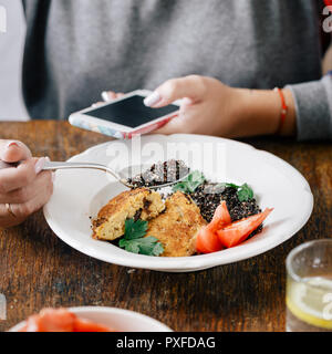 Frau vegetarische, die Bilder von Nahrung, die er auf dem Smartphone isst Stockfoto