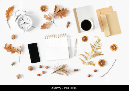 Flach Herbst feminine home office Arbeitsbereich mit Wecker Notepad, Umschlag, Tasse Kaffee, Karte und trockene Blätter im Herbst, Ansicht von oben. Stilvolle Büro Stockfoto