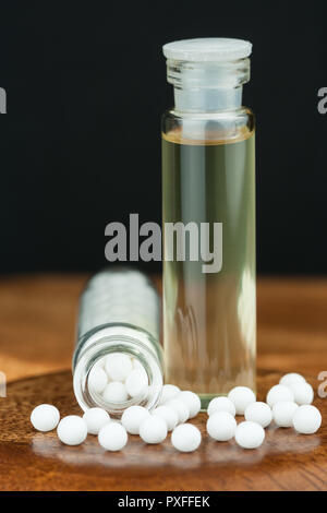 Nahaufnahme der homöopathischen Medizin, bestehend aus den Pillen (von eine inerte Substanz - Zucker/Lactose) und Flüssigen homöopathischen Substanz. Flache Freiheitsgrad. Stockfoto