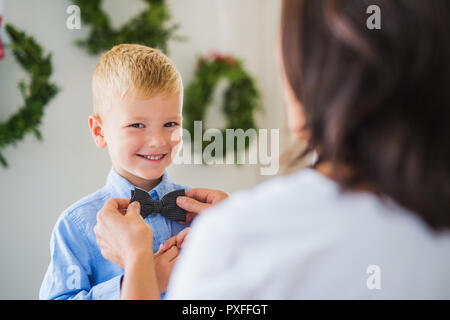 Eine nicht erkennbare Großmutter, eine Fliege auf einem kleinen Jungen zu Hause an Weihnachten. Stockfoto