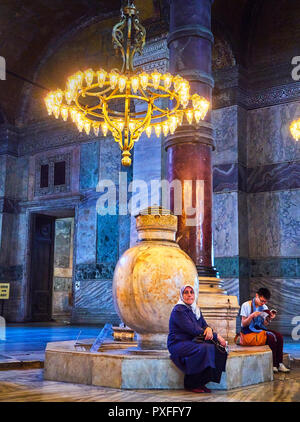 Zwei Touristen, einem arabischen und einem Asiatischen, Ruhe vor einem der Marmor Gläser im Langhaus der Hagia Sophia. Istanbul, Türkei. Stockfoto