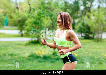 Schöne junge Frau im grünen Sommer Park läuft. Stockfoto