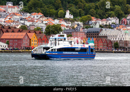 Katamaran Rygertroll geht Fjord sightseein, Abfahrt von Bergen, Norwegen. Berg Fløyen hinter Bryggen Kai, die alte hanseatische Architektur. Stockfoto