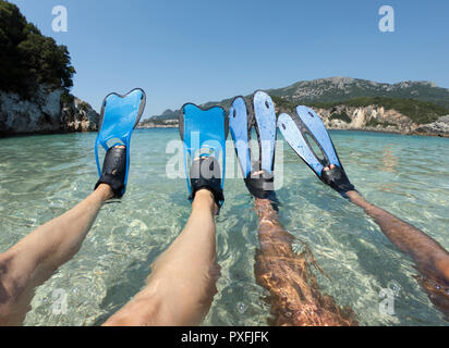 Schnorchler paar Entspannen am Strand. Gebräunte Beine in blauen Flossen, flossen im kristallklaren Meerwasser Stockfoto