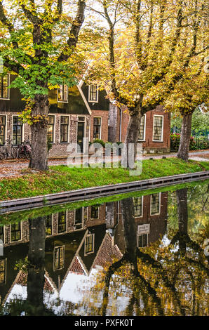 Edam, Niederlande, 7. Oktober 2018: Canal Häuser mit Holz- und Klinkerfassaden und Bäume im Herbst Farben sich im ruhigen Wasser des IJe Stockfoto