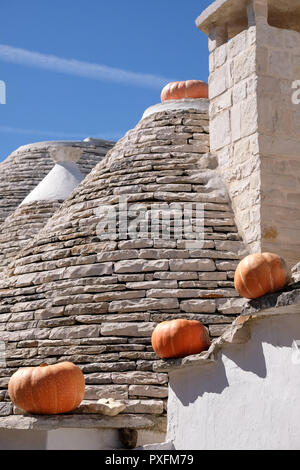 Gruppe von Trockenmauern Trulli auf einer Straße in der Aia Piccola Wohngegend von Alberobello. Kürbisse auf die traufe Halloween zu feiern. Stockfoto