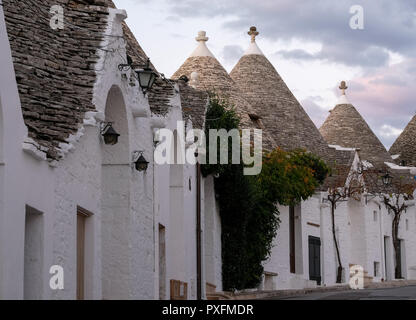 Ansicht der traditionellen weißen Trockenmauern Trulli auf einer Straße im Stadtteil Monti Bereich von Alberobello in Apulien, Italien. Stockfoto