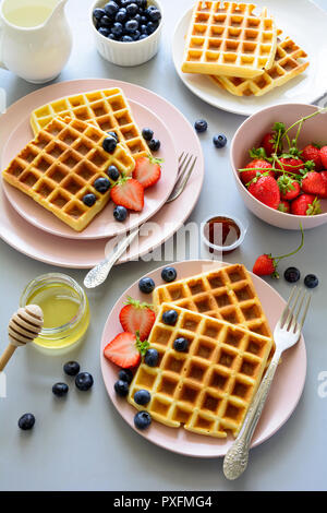 Belgische Waffeln mit Erdbeeren und Honig auf grauem Hintergrund. Gesundes Frühstück Konzept Stockfoto