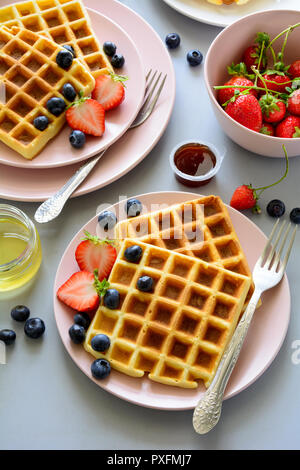 Belgische Waffeln mit Erdbeeren und Honig auf grauem Hintergrund. Gesundes Frühstück Konzept Stockfoto