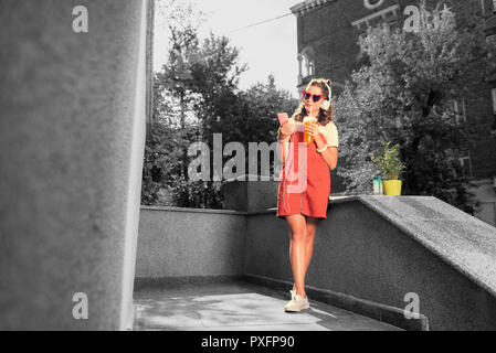 Moderne Student trägt leuchtend rote Sonnenbrille draußen für Ihren Freund Stockfoto
