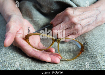 Zerbrochene Gläser in die Hände einer alten Frau. Teil des Körpers. Stockfoto