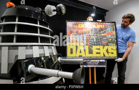 Prop Store Mitarbeiter Matt Geschichte Orte ein Plakat für die 1965 Film Dr Who und die Daleks neben einem Replikat Dalek auf dem Display während eine Vorschau auf die bevorstehende Kino Plakat Auktion an der Prop Shop Head Office in der Nähe von Rickmansworth. Stockfoto