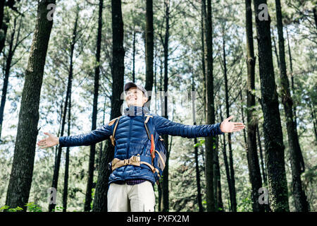 Attraktiven asiatischen Mann mit Rucksack genießen Panorama auf den Wald Stockfoto
