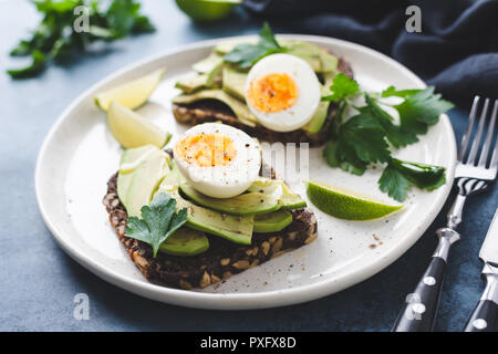 Gesunder Roggen Toast mit Avocado, Ei, Feta Käse auf Platte, Detailansicht. Frühstück, Snacks und Mittagessen essen Stockfoto