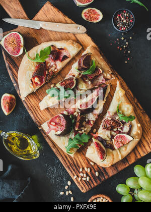 Pizza oder Fladenbrot mit Bild, Schinken, Parmesan, Rucola auf Holz Schneidebrett, Ansicht von oben Stockfoto