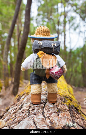 Süße kleine Teddybär backpacker Reisen mit Vintage miniatur Anlagen entlang Baumstamm durch Wald Stockfoto