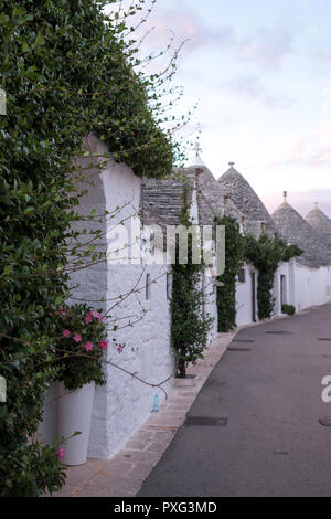 Ansicht der traditionellen weißen Trockenmauern Trulli auf einer Straße im Stadtteil Monti Bereich von Alberobello in Apulien, Italien. Stockfoto