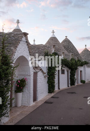 Ansicht der traditionellen weißen Trockenmauern Trulli auf einer Straße im Stadtteil Monti Bereich von Alberobello in Apulien, Italien. Stockfoto