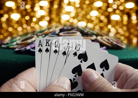 Montreal, Kanada, 21. Oktober, 2018. Hände halten eine Poker Hand von einem Royal Flush mit einem Stapel von Casino Chips. Credit: Mario Beauregard/Alamy Live Stockfoto