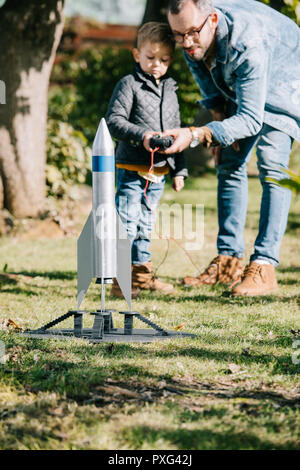 Vater und Sohn starten Modell Rakete zusammen an einem sonnigen Tag Stockfoto