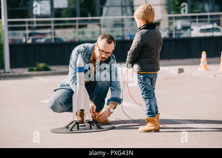 Vater und Sohn starten Modell Rakete zusammen im Freien Stockfoto