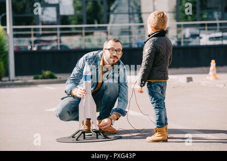 Vater und Sohn starten Modell Rakete zusammen im Freien Stockfoto