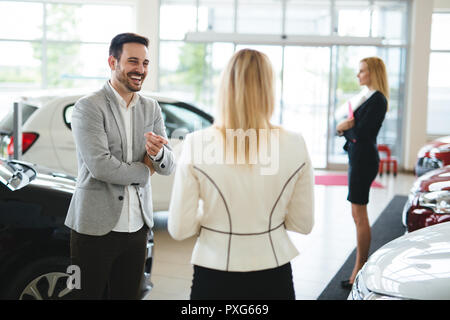 Händler zeigen ein neues Automodell zu potenziellen Kunden Stockfoto