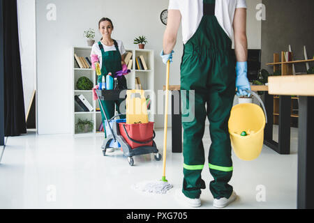 7/8 Schuß von jungen Reiniger verschiedene Reinigungsgeräte im Büro Stockfoto