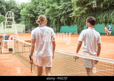 Athletische Tennisspieler in Weiß Sportswear mit hölzernen Schläger zu Fuß in der Nähe von Netto auf Gericht Stockfoto