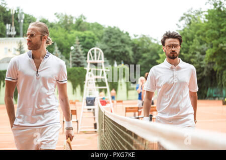 Athletische Tennisspieler mit hölzernen Schläger zu Fuß in der Nähe von Netto auf Gericht Stockfoto