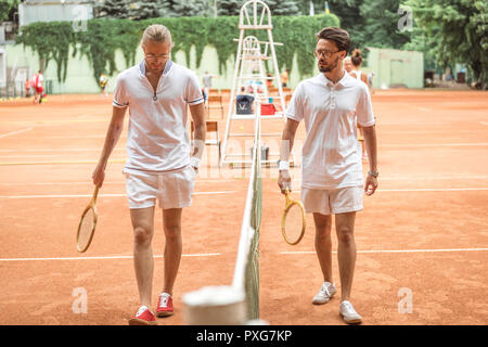 Tennis Spieler mit hölzernen Schläger zu Fuß in der Nähe von Netto auf Gericht Stockfoto