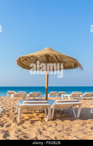 Einer flechtweide Strand Sonnenschirm mit Liegestühlen am blauen Meer Stockfoto