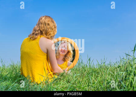 Rothaarige Frau sitzt an ihrem Spiegelbild außerhalb suchen Stockfoto