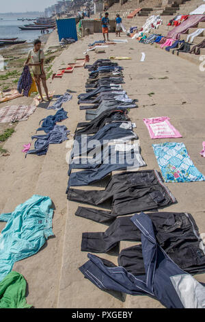 Wäscheservice Tag auf dem Ganges, Varanasi, Uttar Pradesh, Indien. Kleidung und Bettwäsche sind im Fluss und verteilen sich auf die Bank des Flusses zu trocknen Waschen Stockfoto