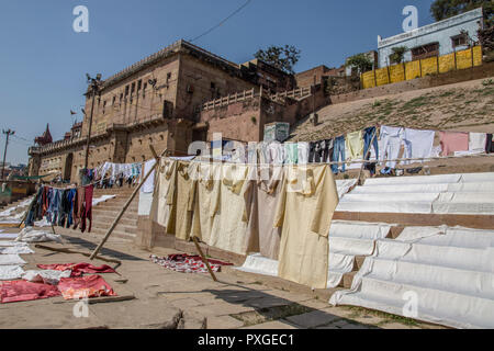 Wäscheservice Tag auf dem Ganges, Varanasi, Uttar Pradesh, Indien. Kleidung und Bettwäsche sind im Fluss und verteilen sich auf die Bank des Flusses zu trocknen Waschen Stockfoto