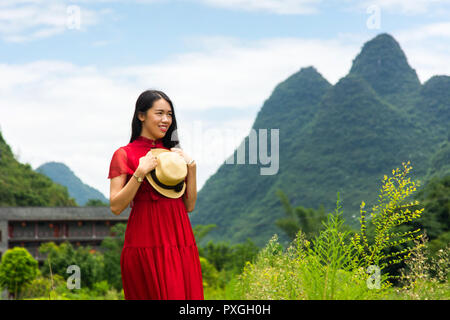 Gerne asiatische Mädchen im roten Kleid und die Aussicht genießen im Karst Natur Stockfoto