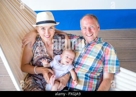 Junges Paar mit Baby Entspannen in der Hängematte auf der Terasse Stockfoto