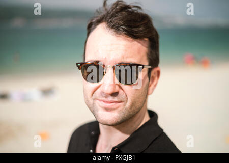Porträt der jungen gutaussehenden Mann Sonnenbrille tragen, in der Nähe der Küste Stockfoto