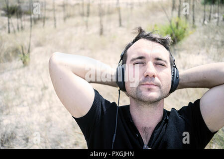 Jungen attraktiven Mann mit schwarzen Musik auf seinem Kopfhörer Stockfoto