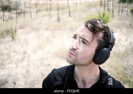 Jungen attraktiven Mann mit schwarzen Musik auf seinem Kopfhörer Stockfoto